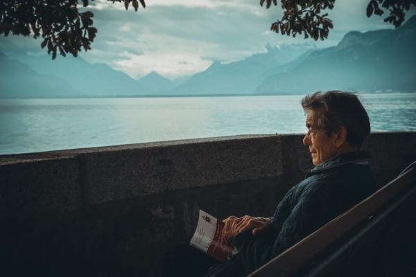Older Man Sitting by a Lake with a Book